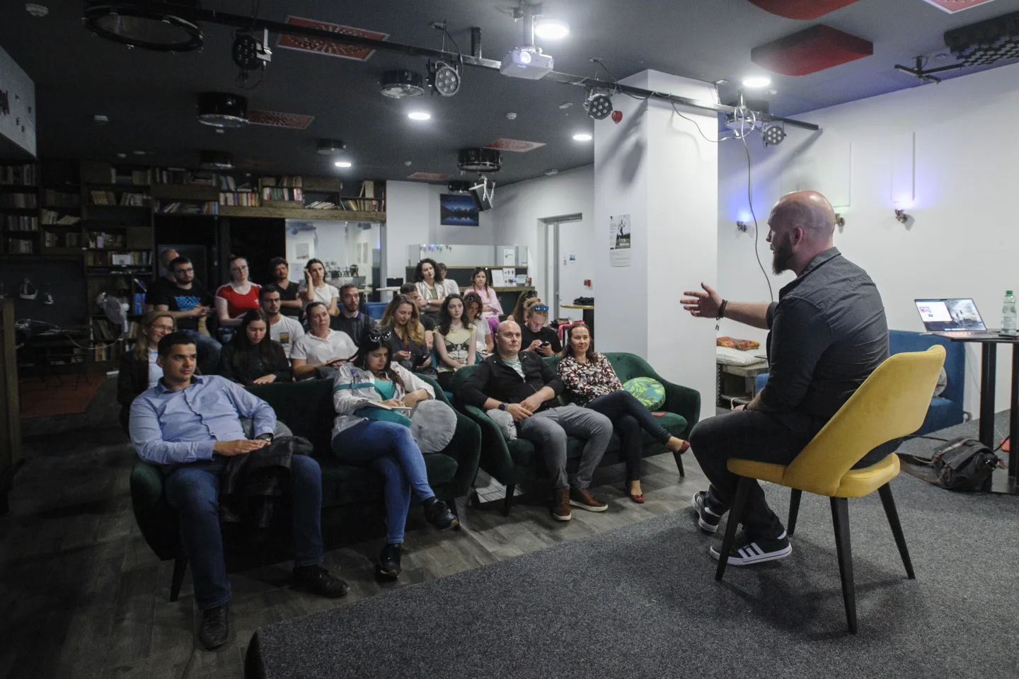 Tom teaching a seated group, gesturing as they listen.